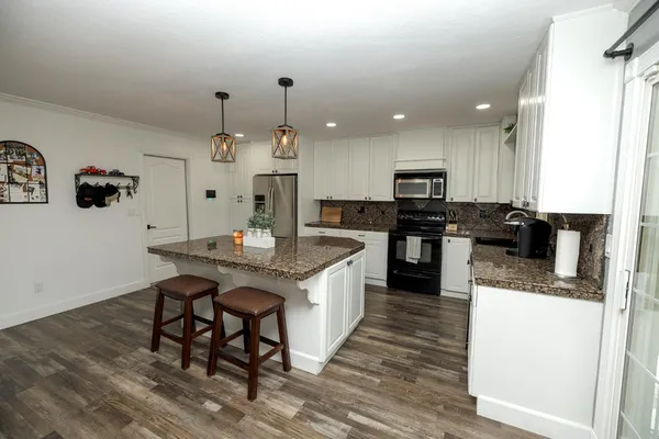 a kitchen with stainless steel appliances kitchen island granite countertop a stove a sink and a refrigerator