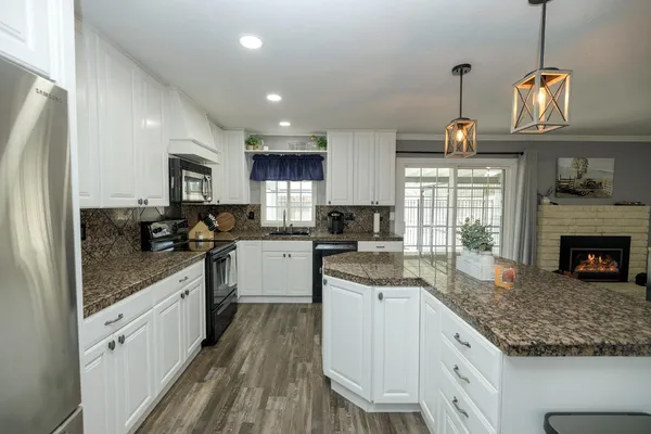 a kitchen with kitchen island granite countertop a sink a counter space appliances and cabinets