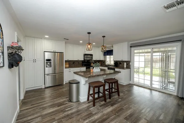 a kitchen with stainless steel appliances a refrigerator a stove a sink dishwasher with a dining table and chairs