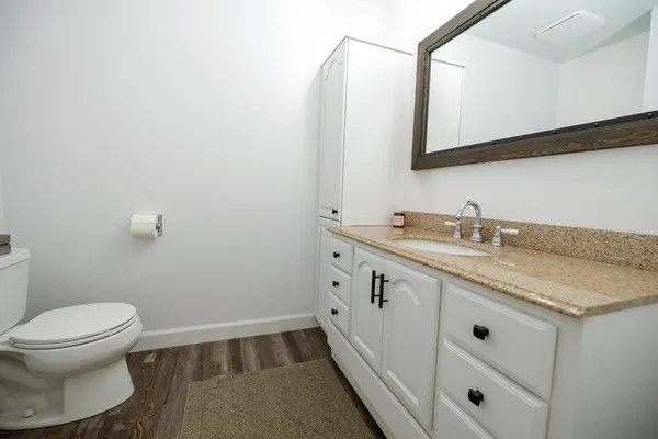 a bathroom with a granite countertop sink mirror vanity and toilet