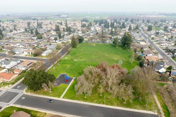 an aerial view of residential houses with outdoor space and trees
