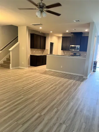 a view of a kitchen with kitchen island a window wooden floor and a refrigerator