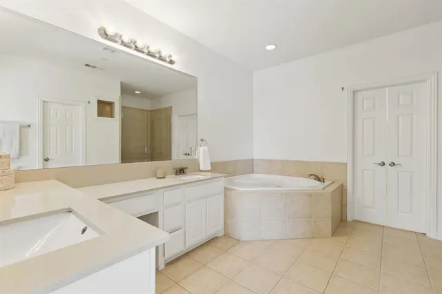 a spacious bathroom with a tub a double vanity sink and mirror