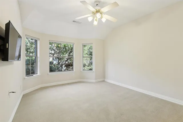 an empty room with windows and chandelier fan