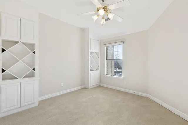 an empty room with windows and chandelier fan