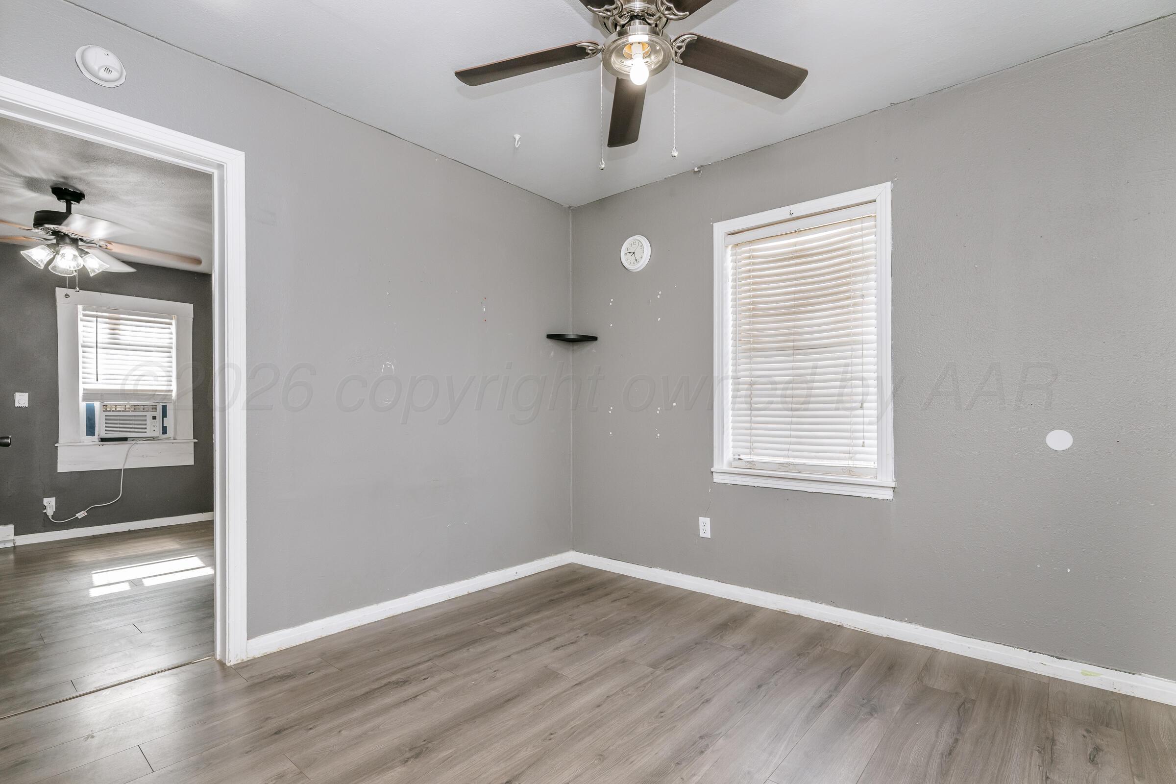 4429 Bowie Street Amarillo, TX 79110 - Photo 11 of 20 an empty room with wooden floor fan and windows
