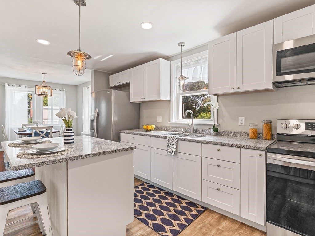 a kitchen with kitchen island granite countertop white cabinets white stainless steel appliances with a sink and dishwasher