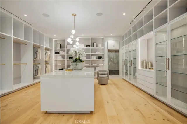 a large white kitchen with granite countertop a large white cabinets and chandelier