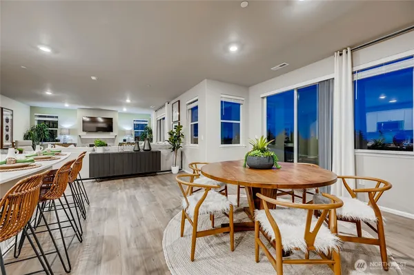 a room with stainless steel appliances kitchen island granite countertop a table chairs and a refrigerator