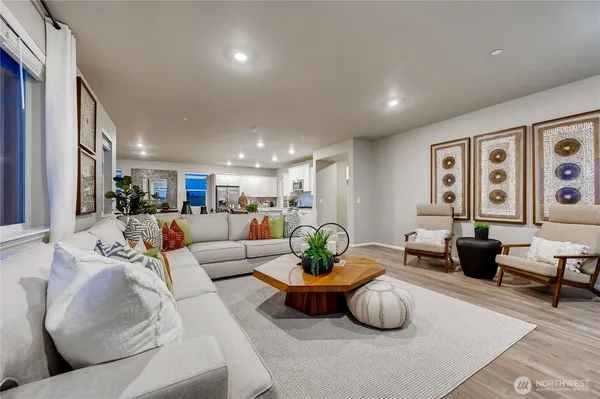 a living room with furniture potted plant and kitchen view