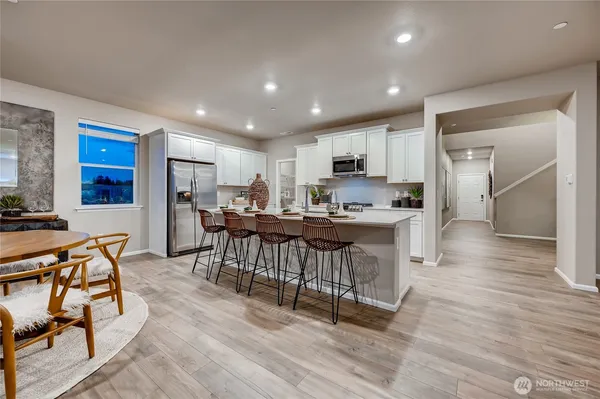 a kitchen with kitchen island a dining table chairs and a refrigerator