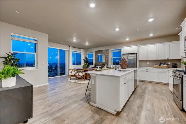 a kitchen with stainless steel appliances a white stove top oven a sink dishwasher and a dining table with wooden floor