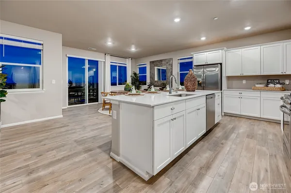 a kitchen with stainless steel appliances granite countertop a sink cabinets and wooden floor