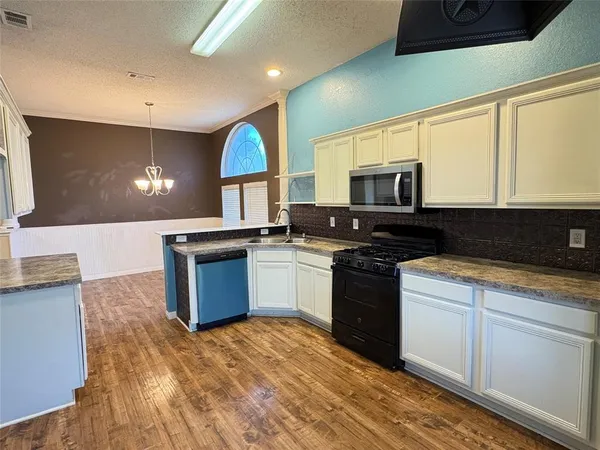 a kitchen with stainless steel appliances granite countertop a stove a sink and a microwave