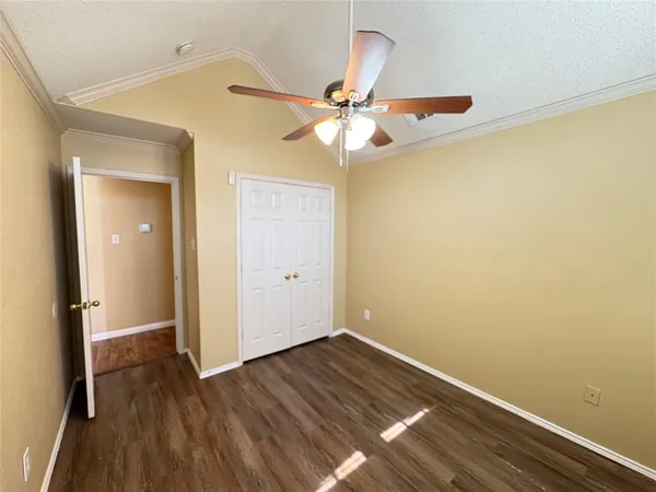 an empty room with wooden floor and fan