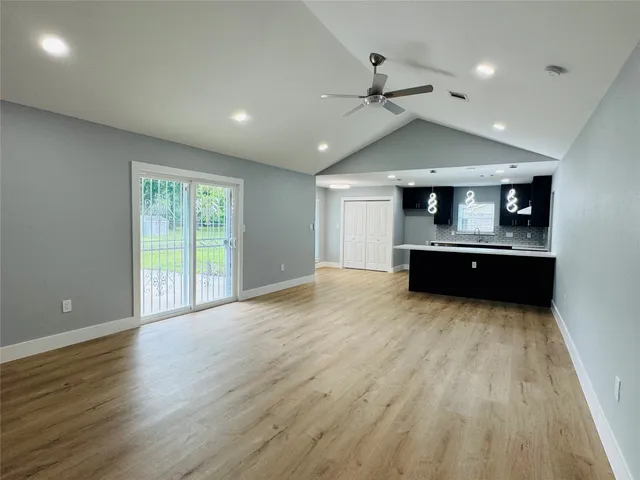 an empty room with wooden floor ceiling fan and windows