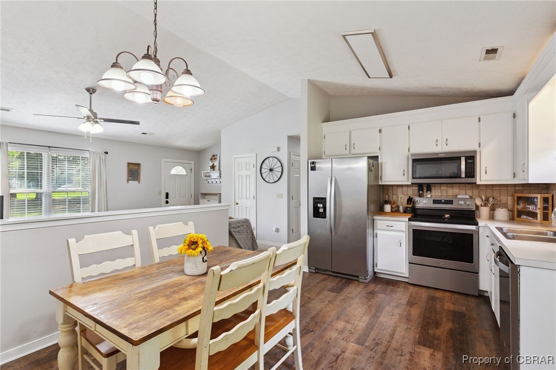 7989 Pinetta Road Gloucester, VA 23061 - Photo 9 of 26 Kitchen featuring appliances with stainless steel finishes, vaulted ceiling, dark wood-type flooring, backsplash, and light countertops