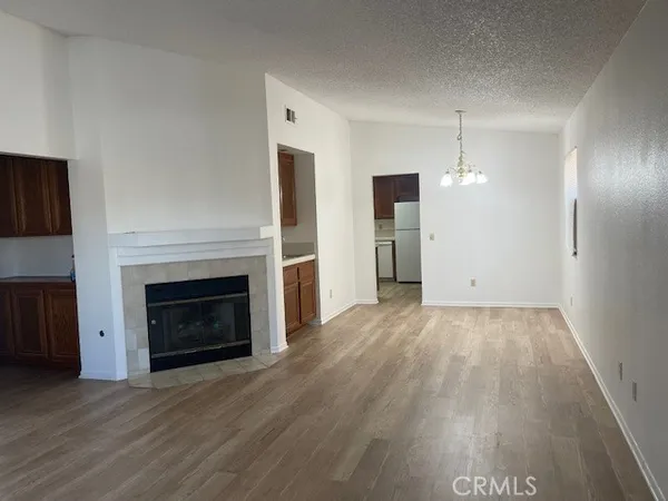 a view of an empty room with wooden floor fireplace and a window