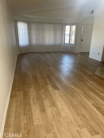 a view of an empty room with wooden floor and windows