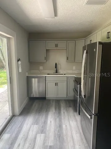 a kitchen with white cabinets and wooden floor
