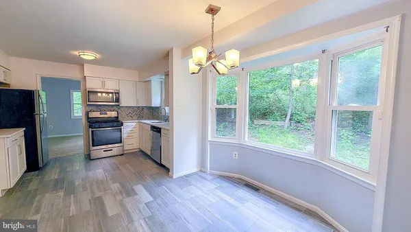 a kitchen with stainless steel appliances granite countertop a refrigerator a sink a stove and a wooden floors