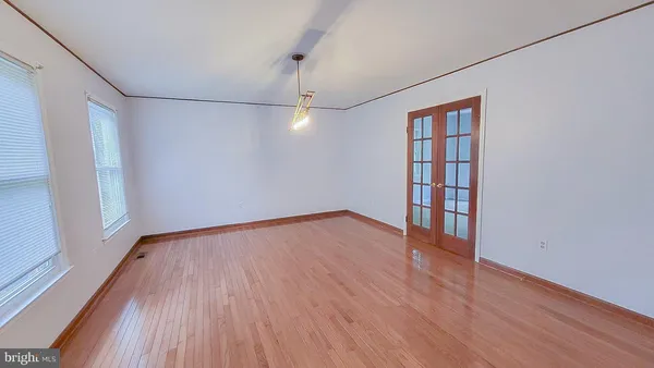 a view of a hallway to a livingroom with wooden floor and stairs