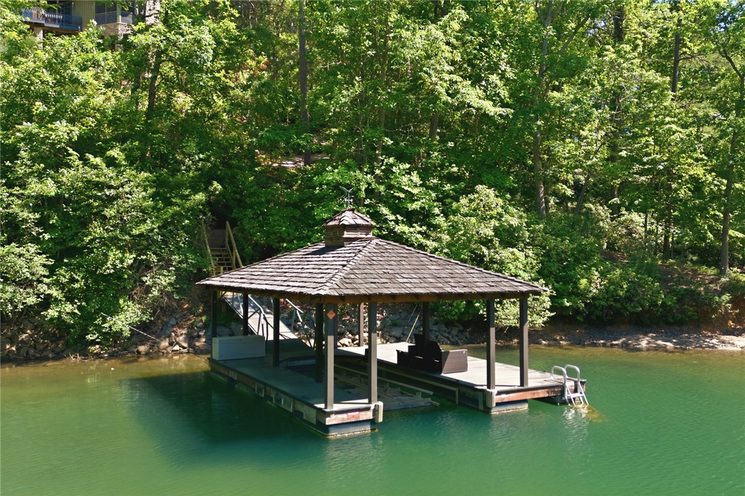 130 River Ridge Road Sunset, SC 29685 - Photo 7 of 47 This tranquil waterfront scene showcases a private boat dock with an inviting covered slip, perfect for lakeside enjoyment.