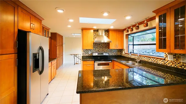a kitchen with stainless steel appliances granite countertop a refrigerator a stove and a sink