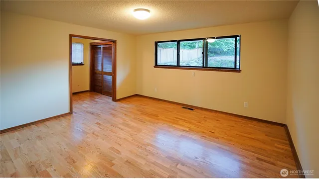 a view of an empty room with wooden floor and a window