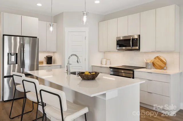 a kitchen with stainless steel appliances a stove a sink a microwave and white cabinets