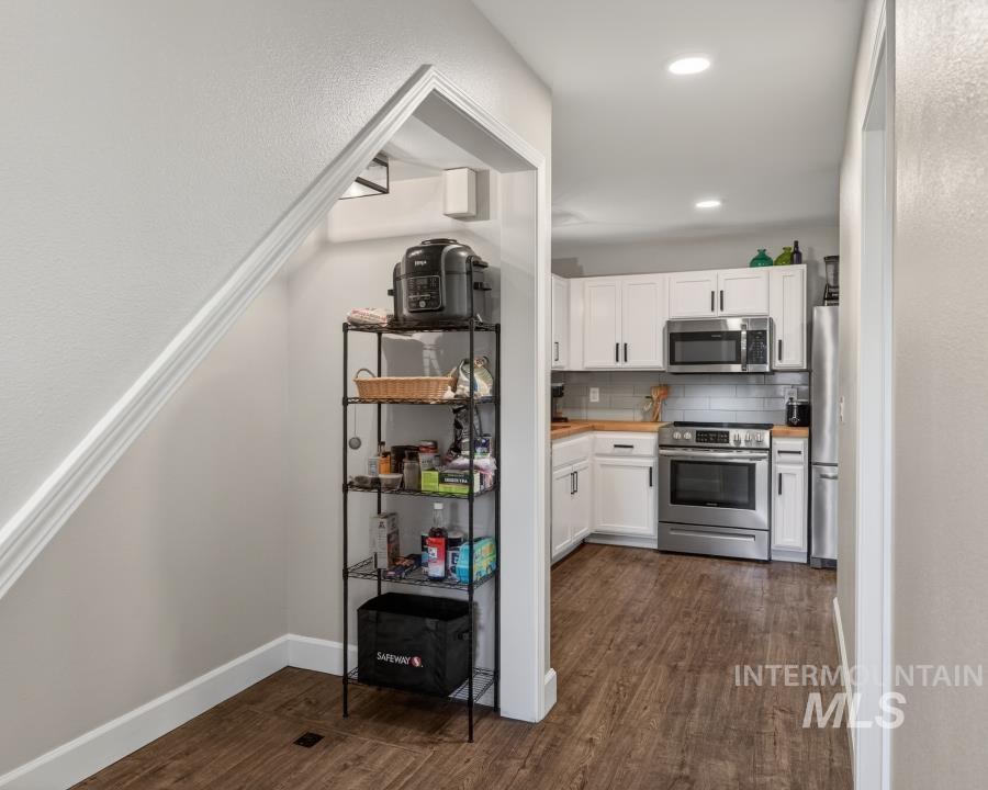1342 Bristol Road Moscow, ID 83843 - Photo 10 of 26 Kitchen featuring stainless steel appliances, white cabinetry, dark wood-style floors, backsplash, and wooden counters