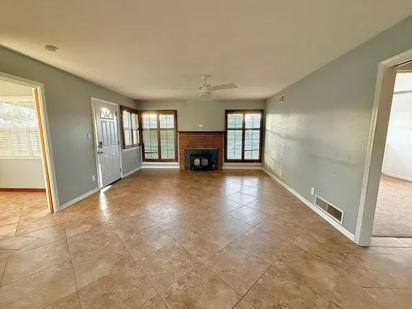 an empty room with windows and fireplace
