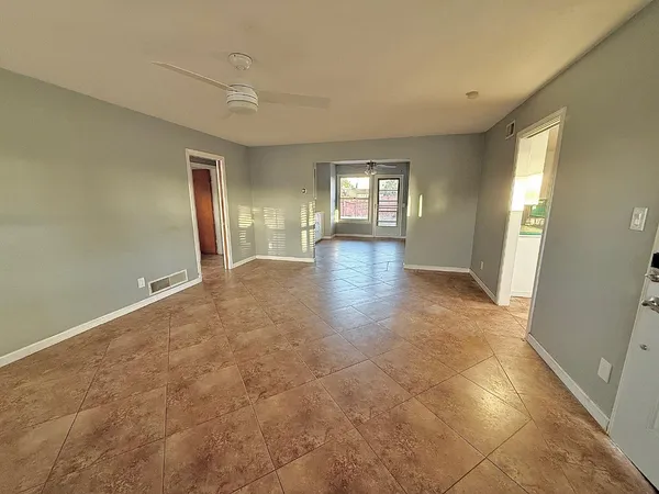 a view of an empty room with window and wooden floor