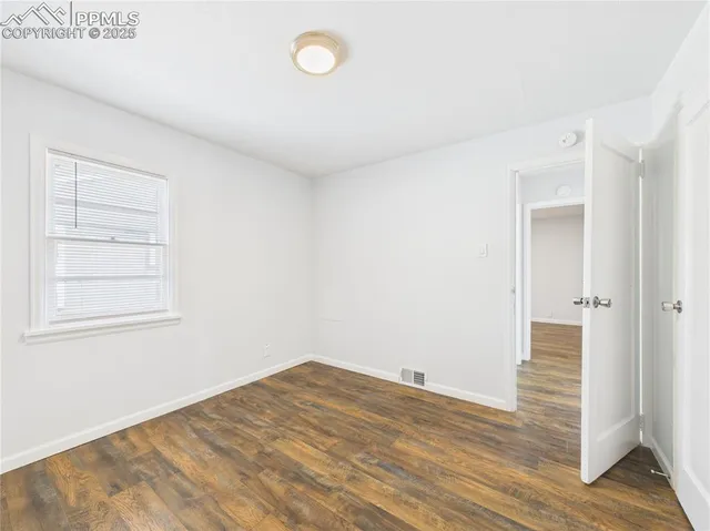 a view of empty room with wooden floor