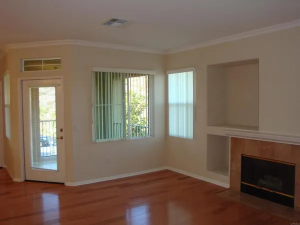 an empty room with wooden floor fireplace and windows