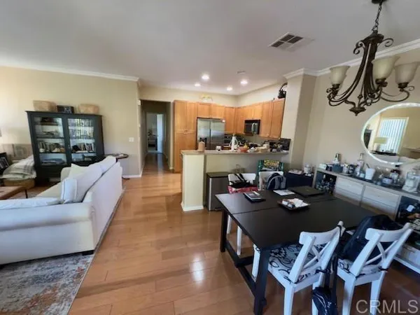 a living room with furniture kitchen view and a wooden floor