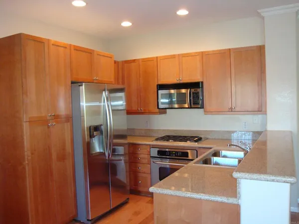 a kitchen with stainless steel appliances granite countertop a refrigerator and a stove top oven