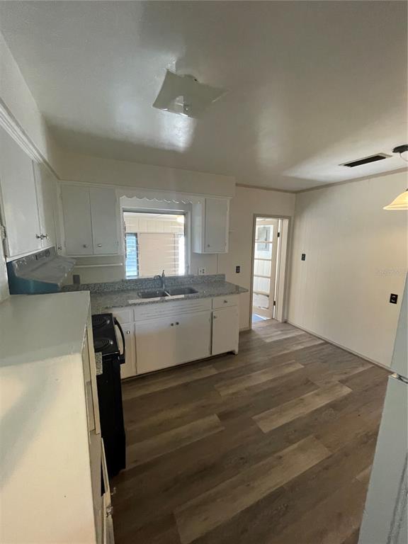 143 East South Street Deland, FL 32724 - Photo 6 of 13 a kitchen with granite countertop white cabinets and wooden floor