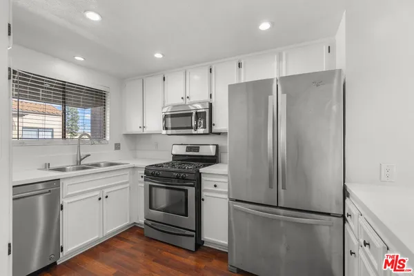 a kitchen with cabinets stainless steel appliances a sink and a window