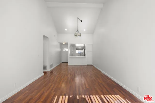 an empty room with wooden floor chandelier and windows