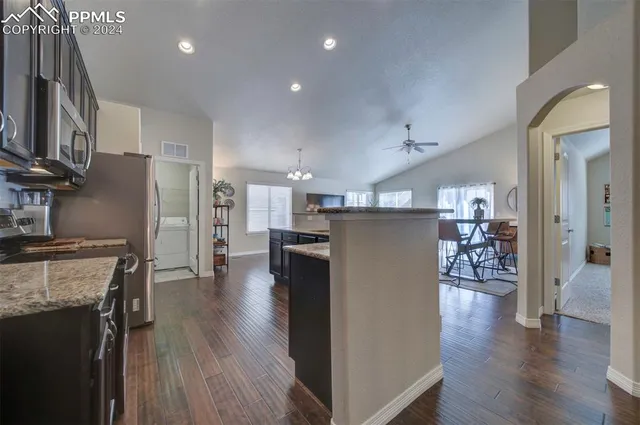 a kitchen with stainless steel appliances granite countertop a refrigerator a stove top oven a sink dishwasher and a refrigerator with wooden floor