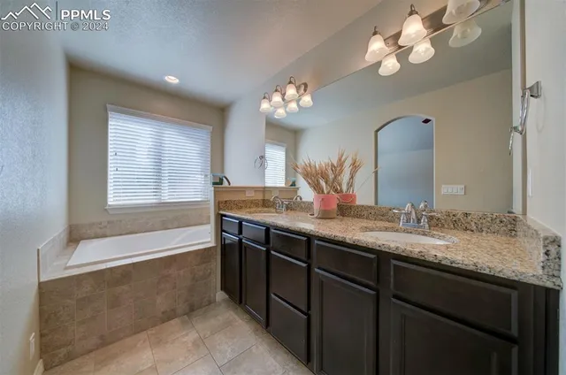 a bathroom with a granite countertop sink a large mirror and a bathtub