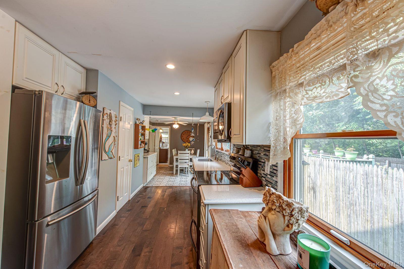 75 Upper Dock Road Kings Park, NY 11754 - Photo 8 of 30 a kitchen with stainless steel appliances a refrigerator a stove a oven with white cabinets and wooden floor