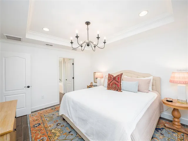 a bedroom with a large bed and a chandelier