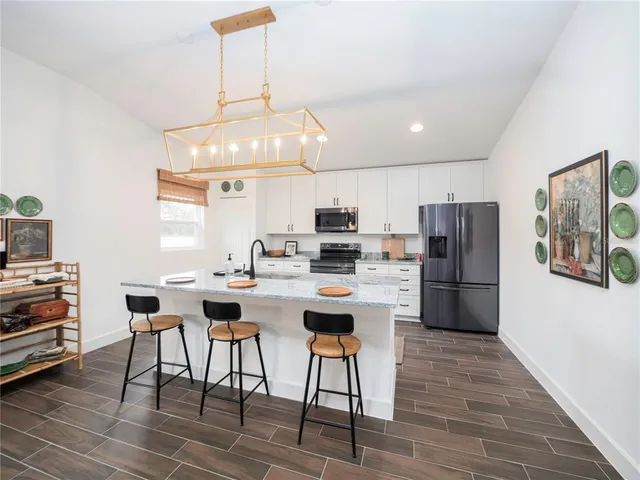 a kitchen with stainless steel appliances a dining table chairs stove refrigerator and cabinets