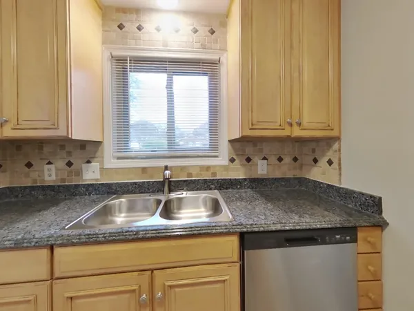 a kitchen with granite countertop a sink window and cabinets