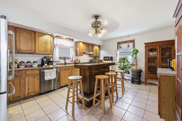 a kitchen with stainless steel appliances granite countertop a stove a sink dishwasher and a refrigerator with wooden cabinets