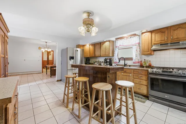 a kitchen with stainless steel appliances a stove a sink cabinets and a dining table