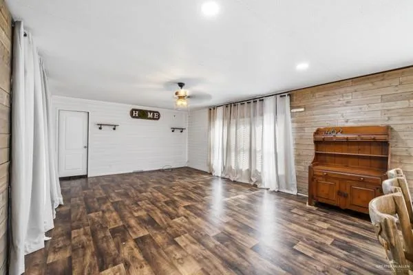 a view of empty room with wooden floor and fan