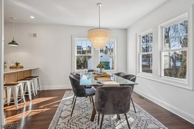 a dining room with wooden floor a chandelier a wooden table and chairs